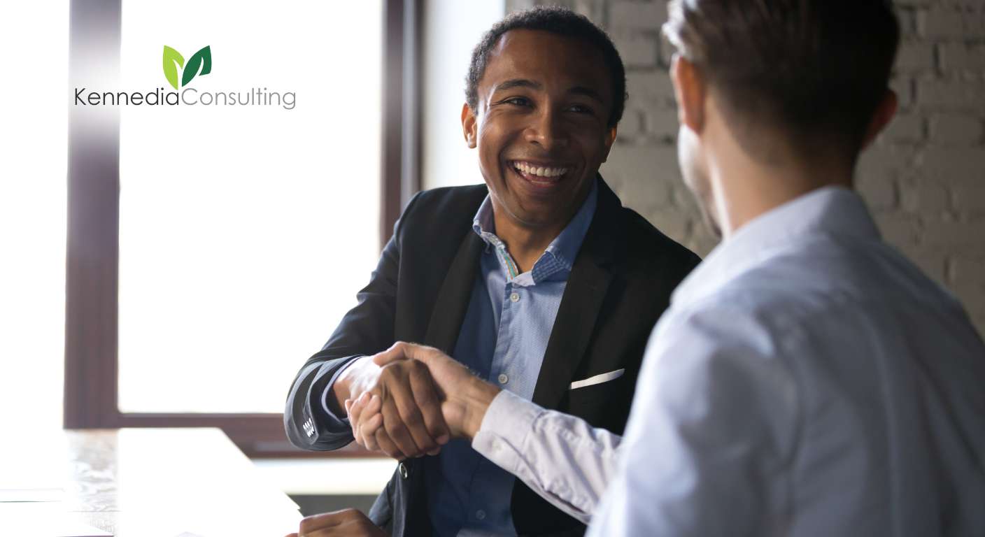 An HR consultant speaking to a client shaking hands indoors.